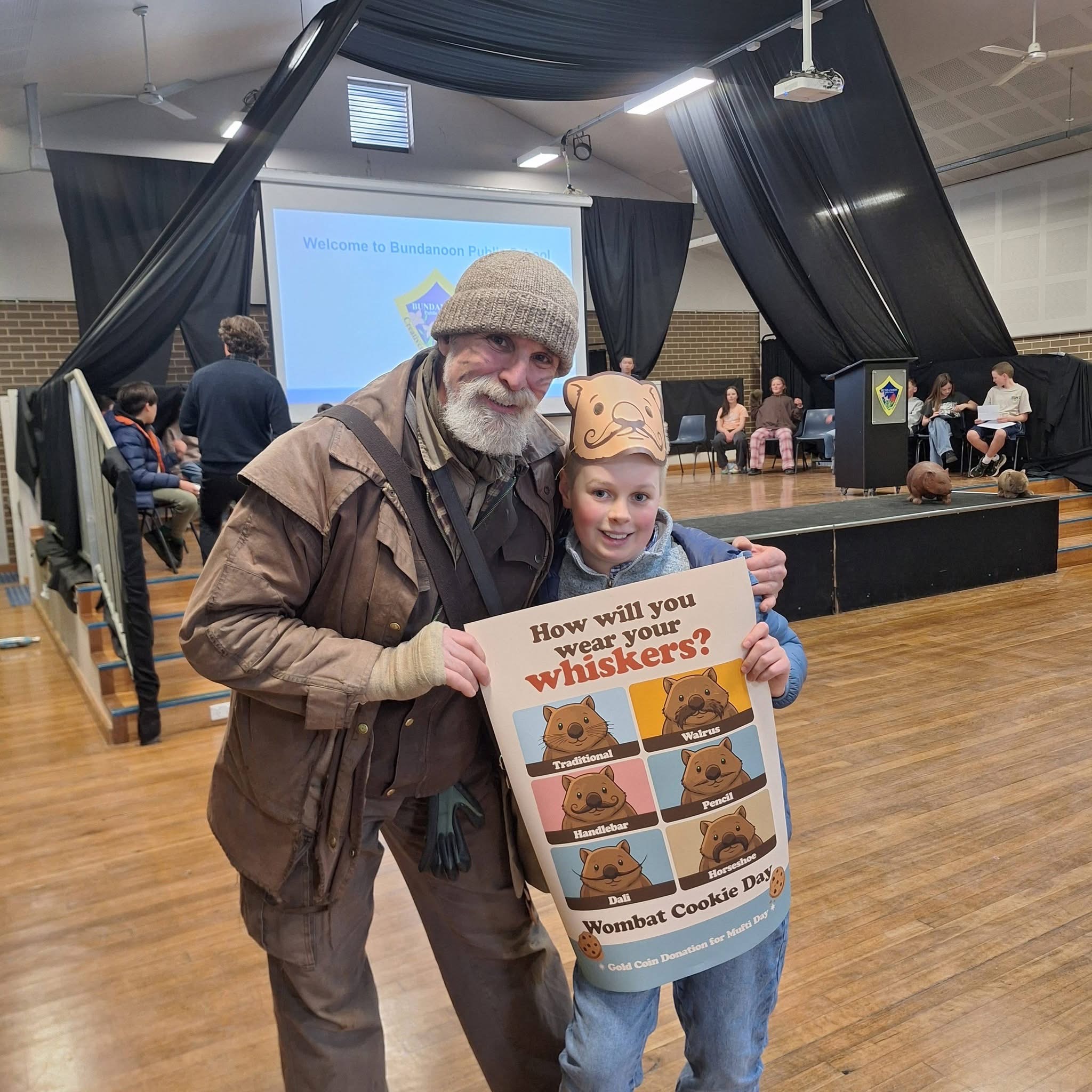 Picture of John Creighton and a student from Bundanoon Public School holding a poster the student designed.